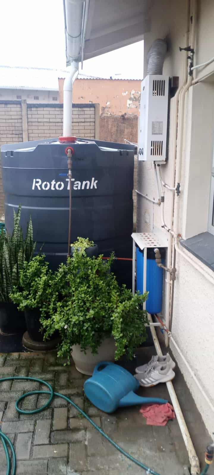 RotoTank water tank installed by Elite Home Finishes, fed from the gutter downpipe with filtration mounted on the wall