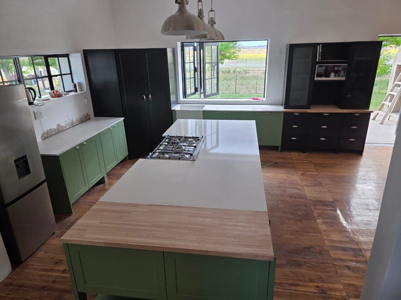 Green shaker kitchen with island and black tall units