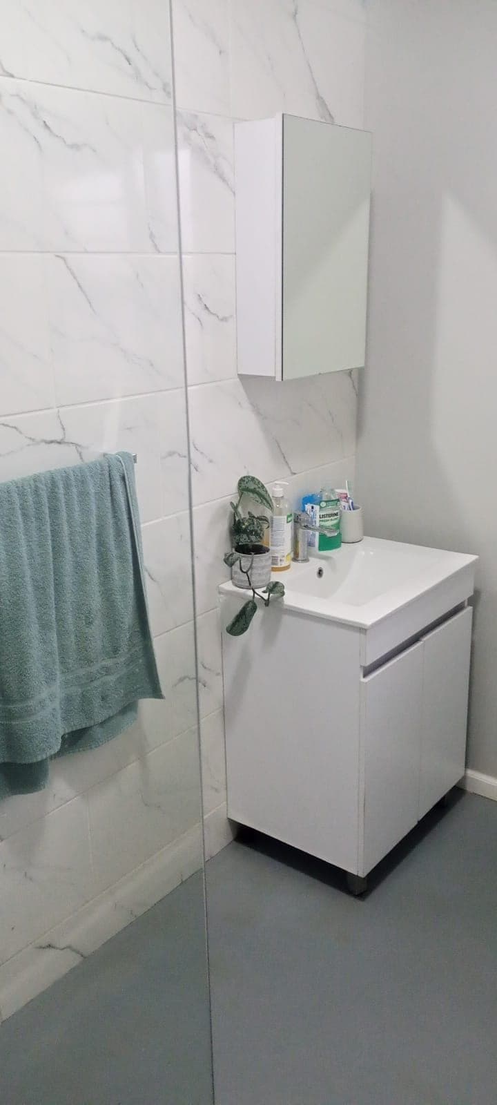 Bathroom renovated by Elite Home Finishes with marble-look wall tiles, white vanity and mirror cabinet