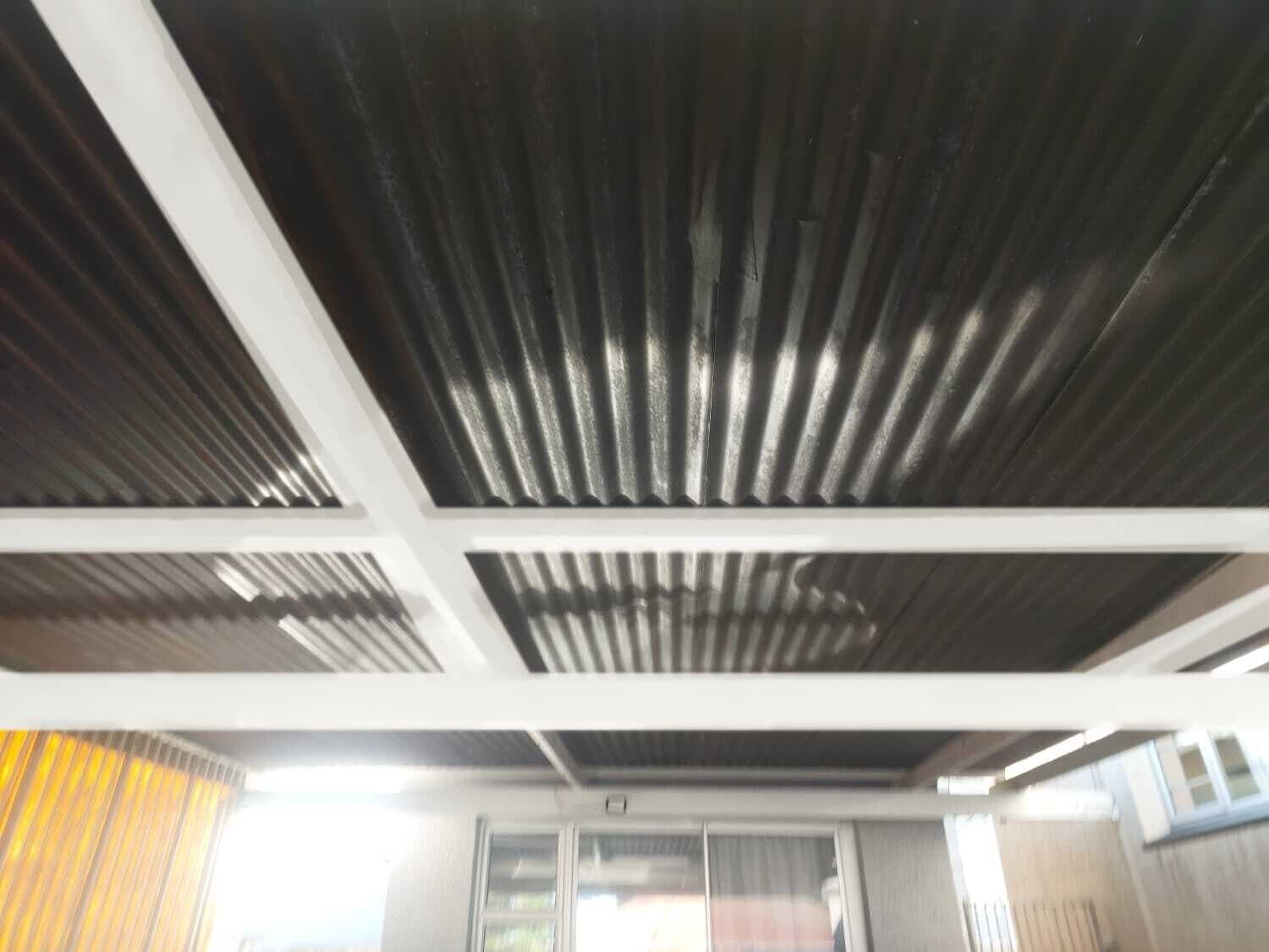 Underside of a carport roof showing the painted steel frame and sheeting