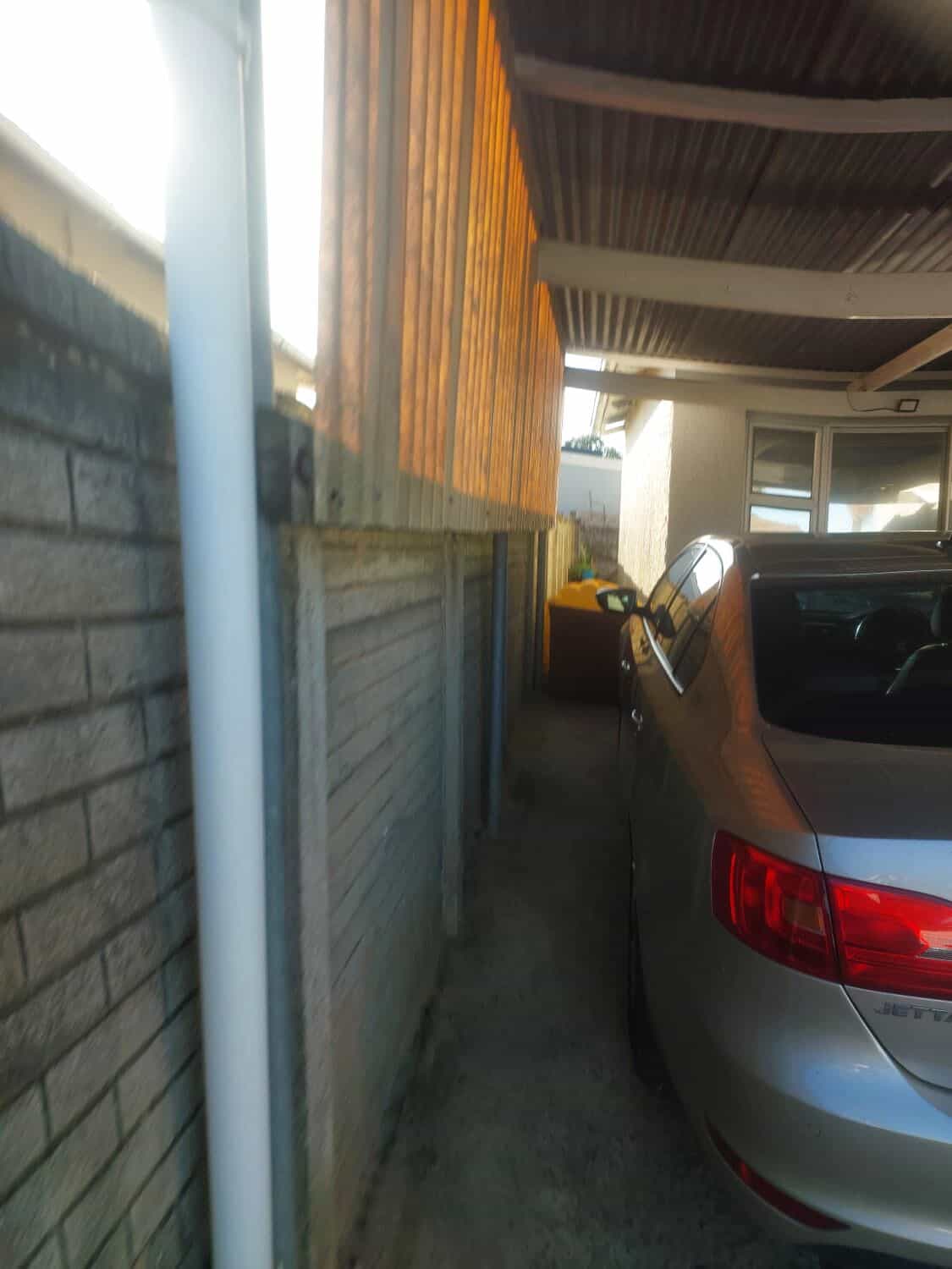 Carport along a side passage with the gutter downpipe run down the wall