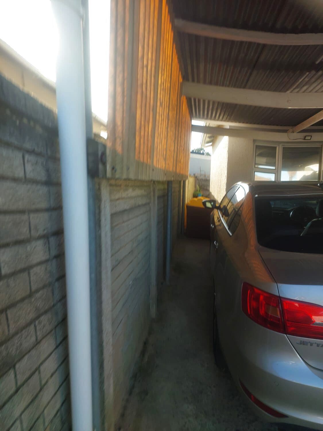 Carport along a side passage with the gutter downpipe run down the wall