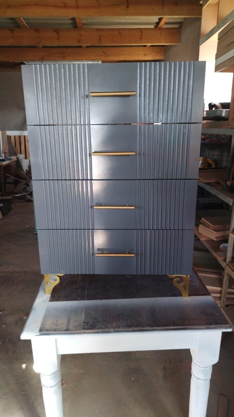 Grey fluted-front chest of drawers with brass handles and feet