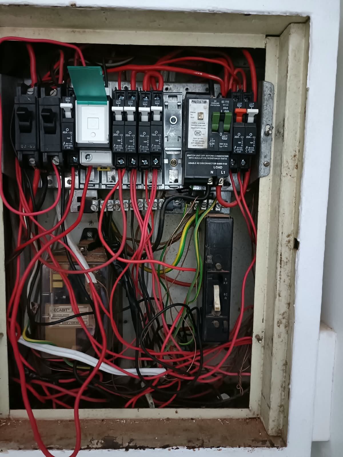 Old distribution board with tangled, unlabelled wiring before Elite Home Finishes replaced the cover