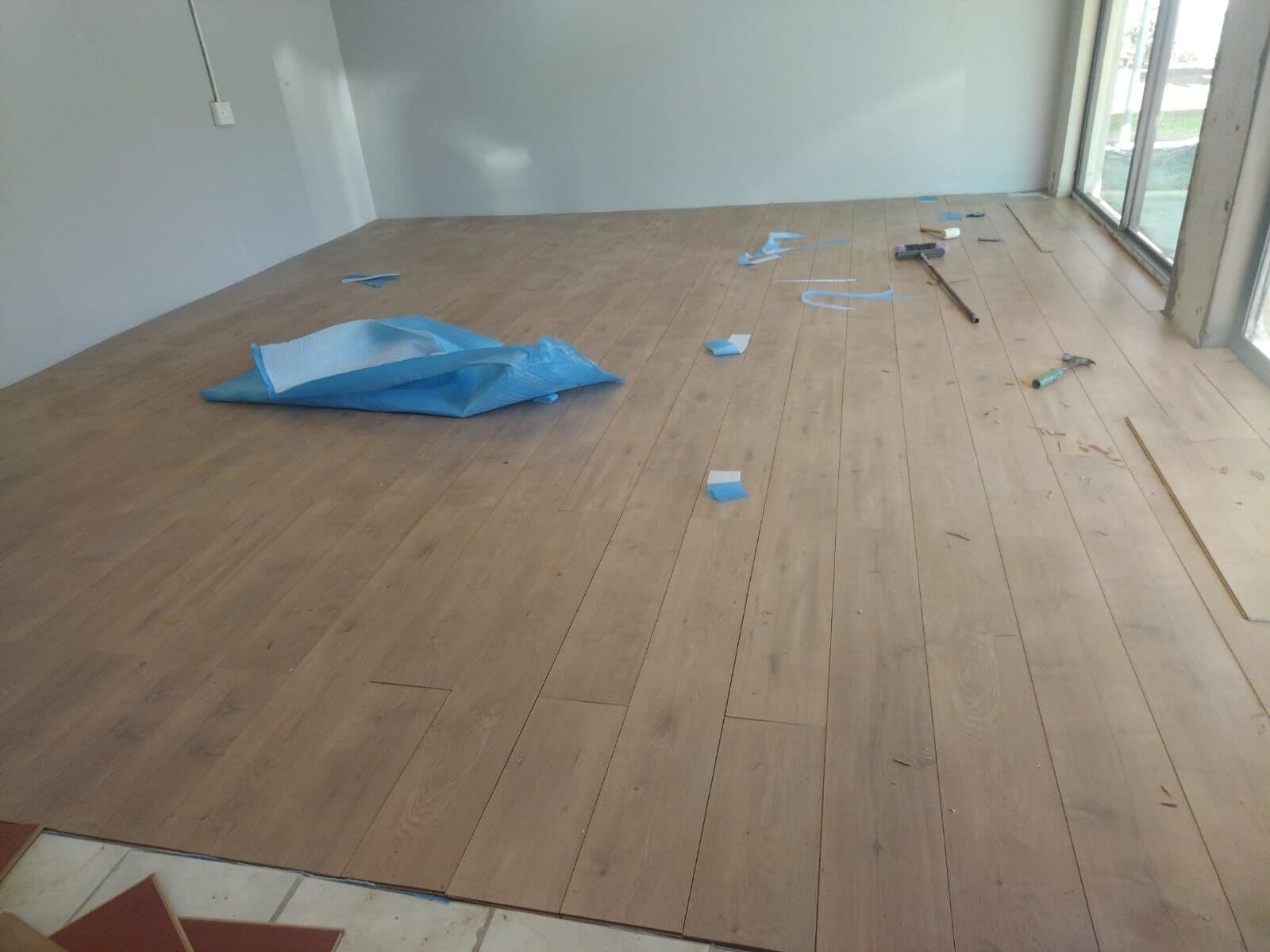 Laminate plank flooring being laid through an open-plan room by our team