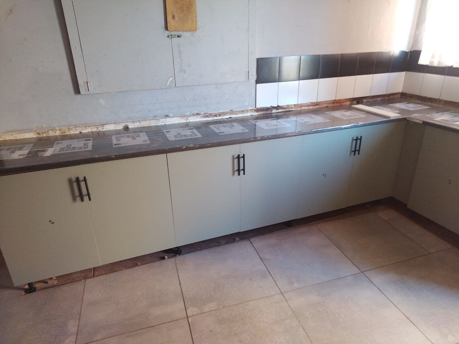 L-shaped grey base cupboards fitted before the worktop and splashback go on