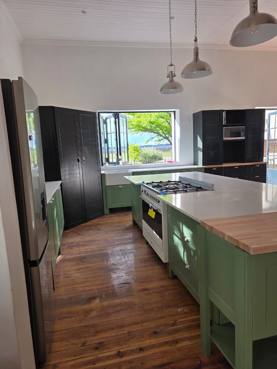 View down the kitchen past the gas stove, island and tall black units