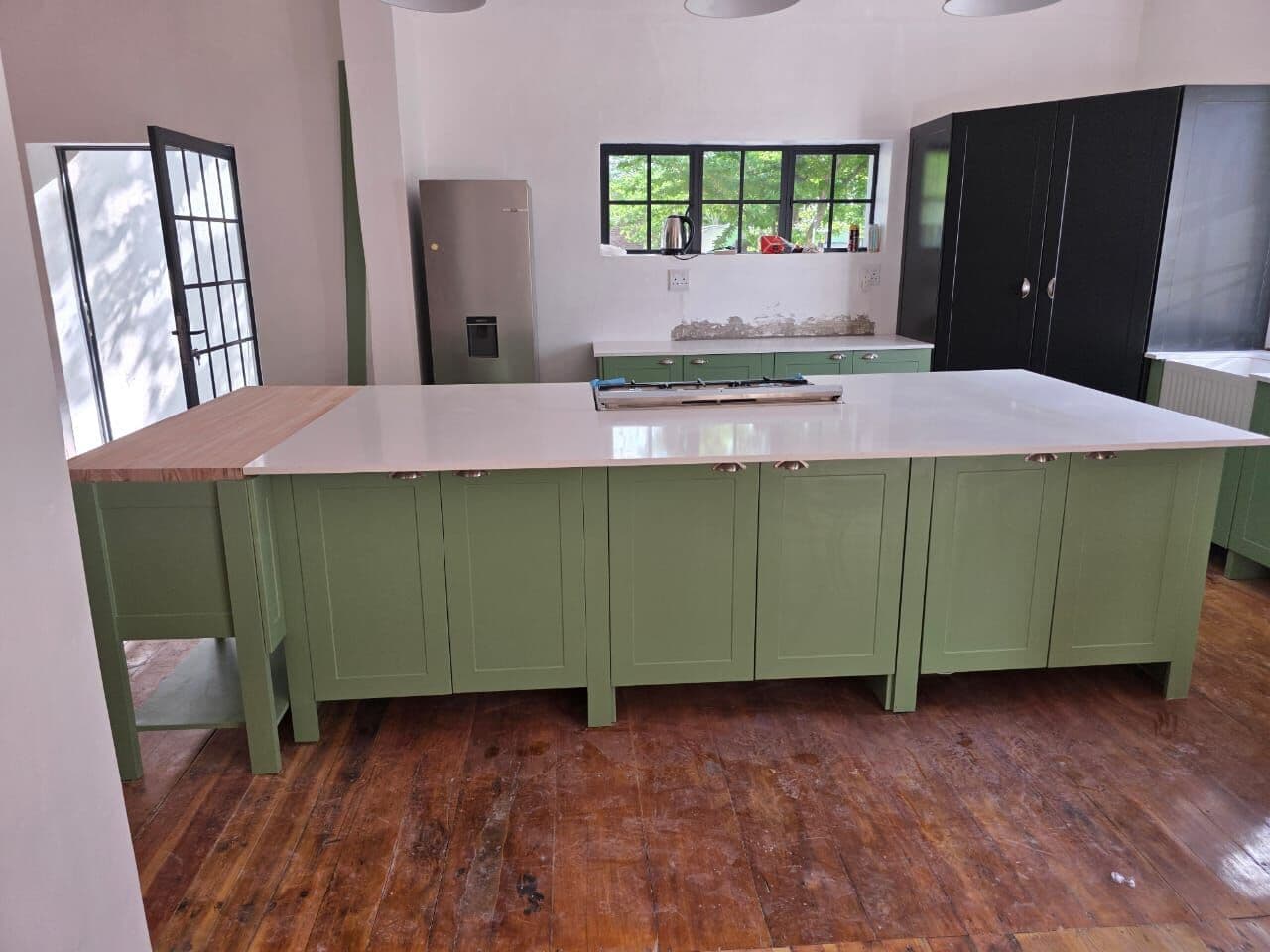 Large green island with white worktop and open shelf below