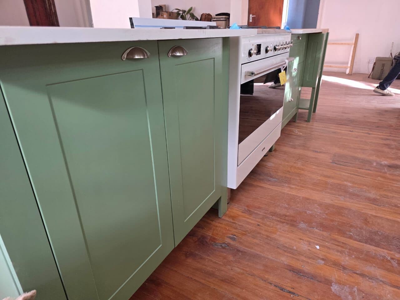 Close-up of green shaker cupboard doors with brass cup handles
