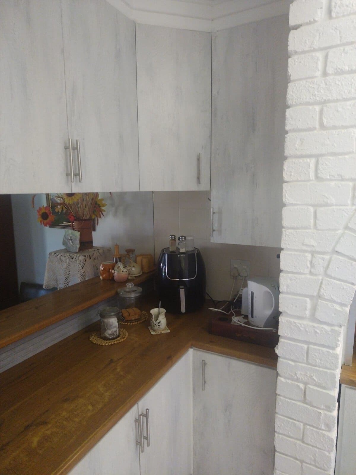 Whitewash kitchen cupboards with timber worktops fitted into a corner by Elite Home Finishes