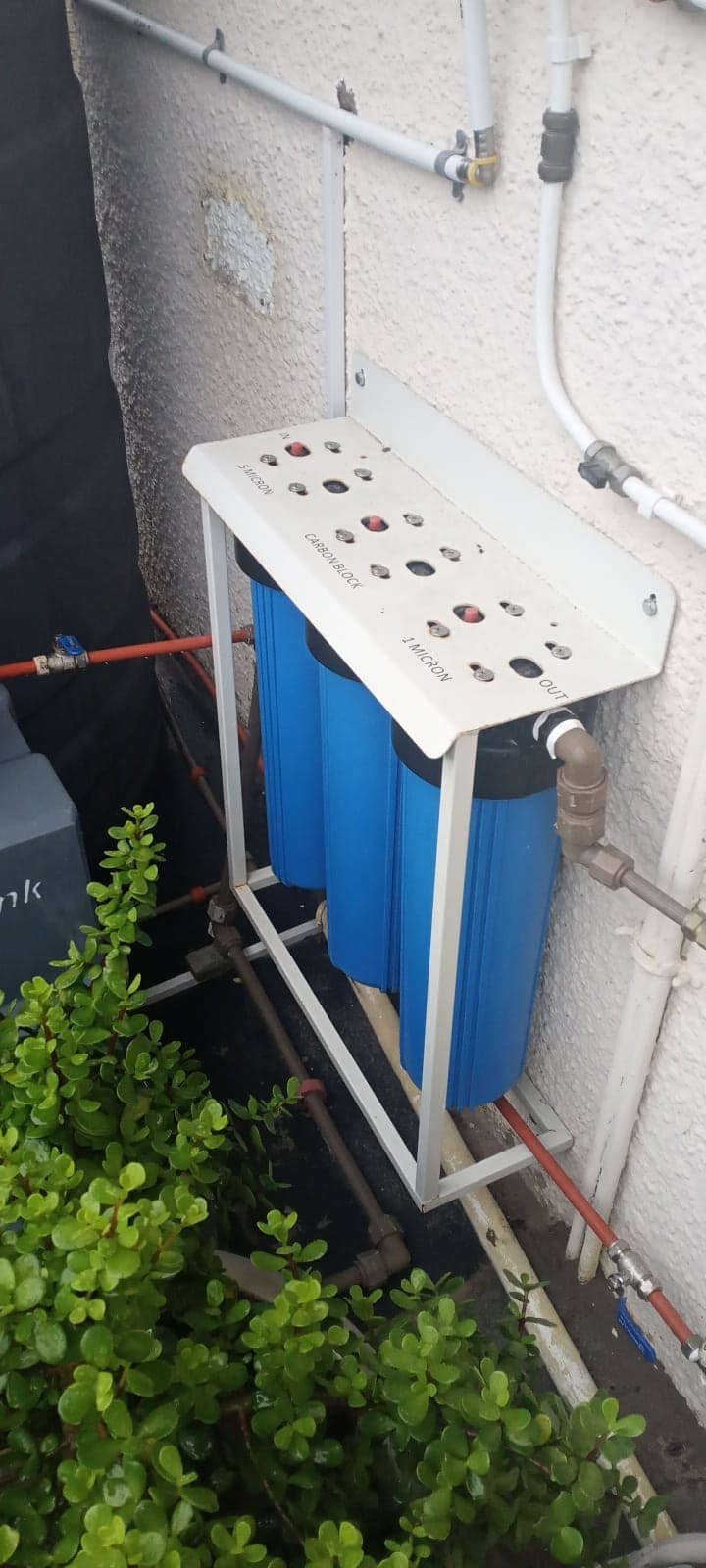 Whole-house 3-stage water filtration by Elite Home Finishes: 5-micron, carbon block and 1-micron filters on a wall rack