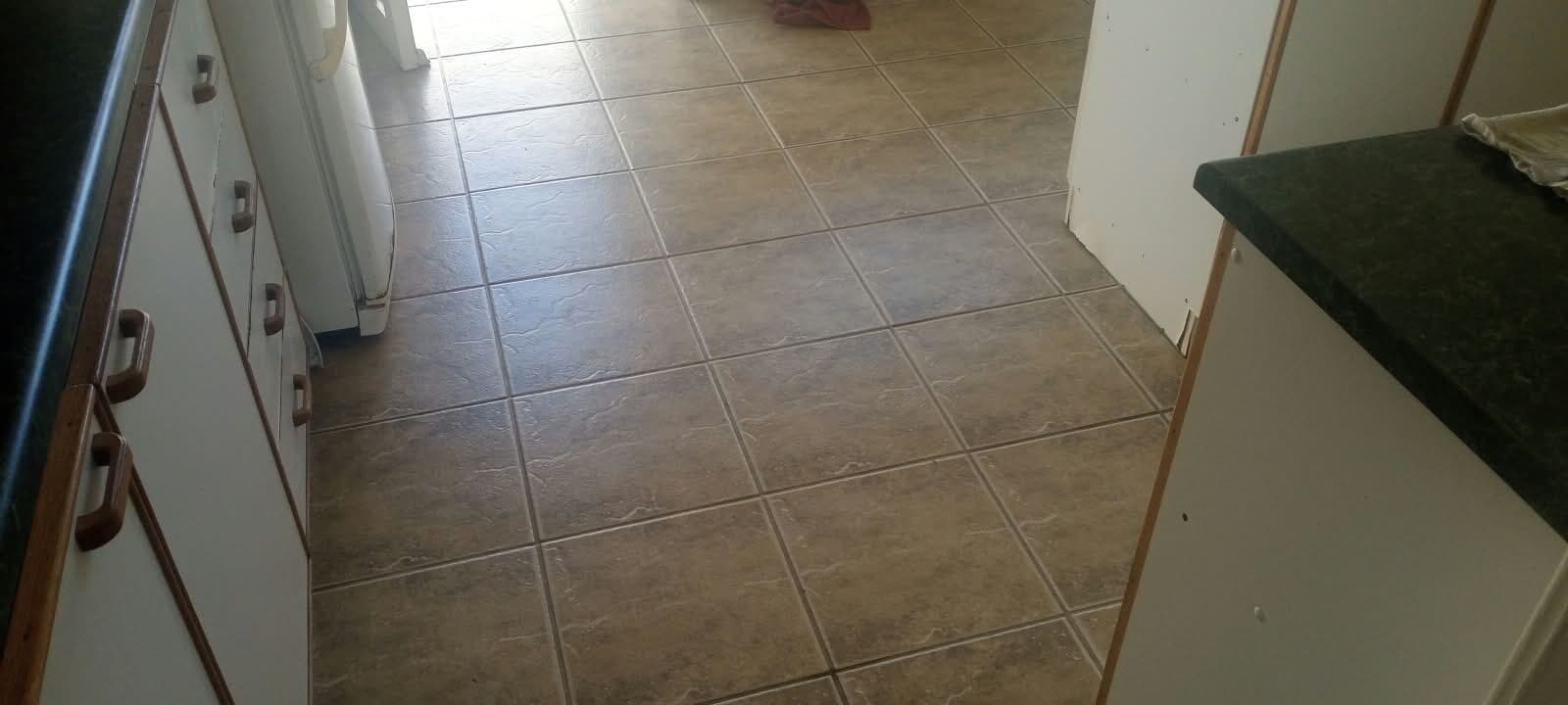 Large-format kitchen floor tiles laid between the cupboards