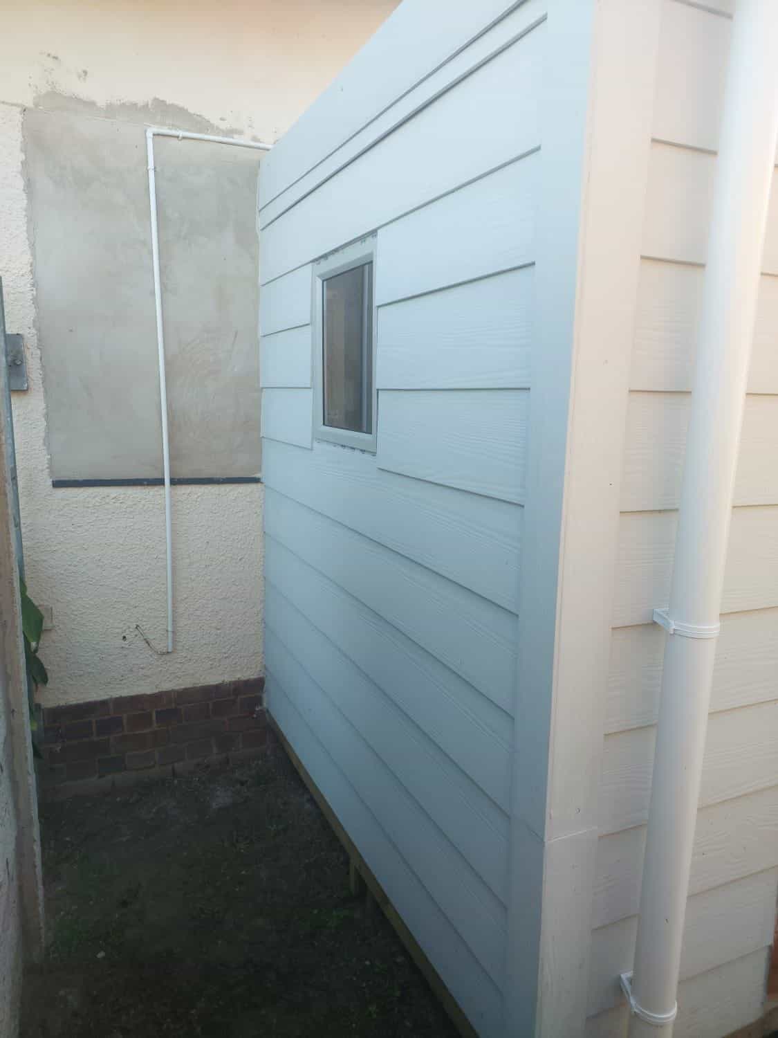 Clad Wendy house with window built on site against the house wall