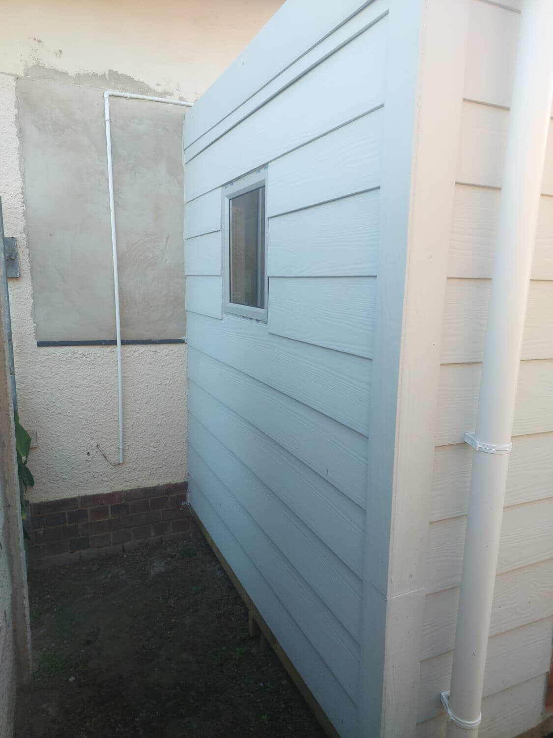 Clad Wendy house with window built on site against the house wall